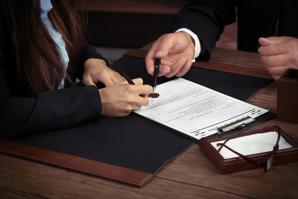 Client signing a durable power of attorney document while an attorney reviews the paperwork
