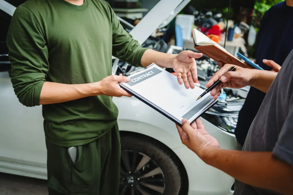 Two people reviewing a signed contract on a clipboard