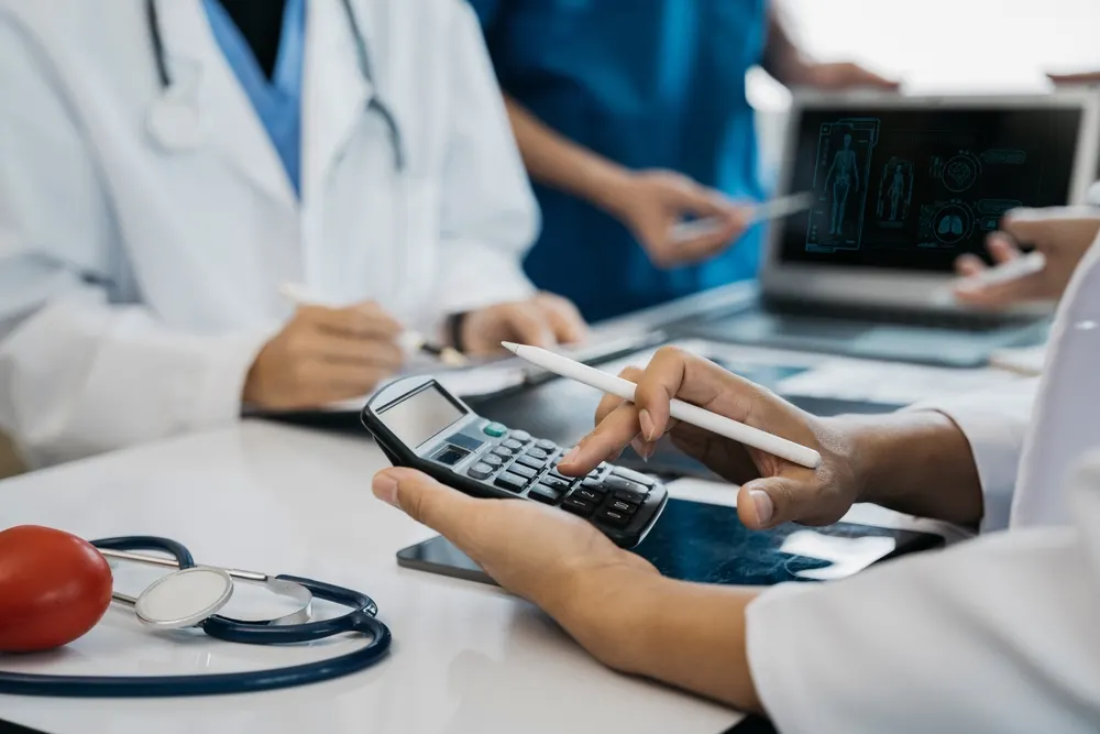 Medical staff reviewing costs and a patient scan with a calculator