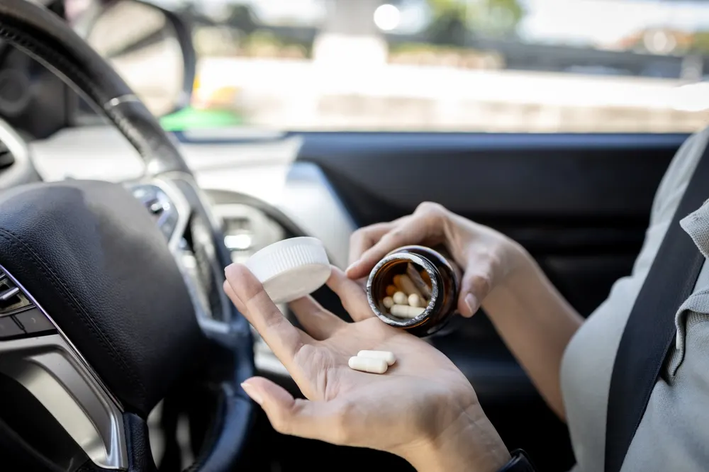 Driver holding medication pills while sitting in a car