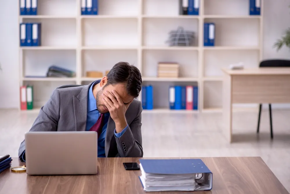 A man holding his head in stress at his desk with legal files
