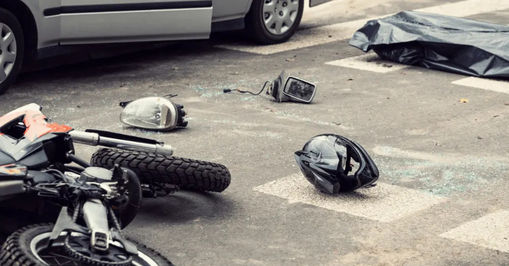 Motorcycle wreckage and a helmet on the road after a crash